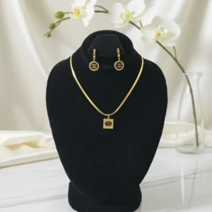 Full view of the gold snake chain necklace and circle drop earrings, inspired by luxury aesthetics, displayed on a black velvet jewelry bust.